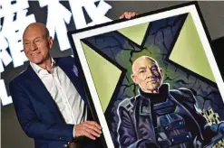  ??  ?? Professor X in the X-Men series’ Patrick Stewart poses for photos with a gift of a painting during a press conference for the film Logan in Taipei. —AFP photos