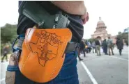  ??  ?? Terry Holcomb, executive director of Texas Carry, happily displays his customized holster on New Year’s Day as he walks to the Capitol for a rally to celebrate Texas becoming an open-carry state.