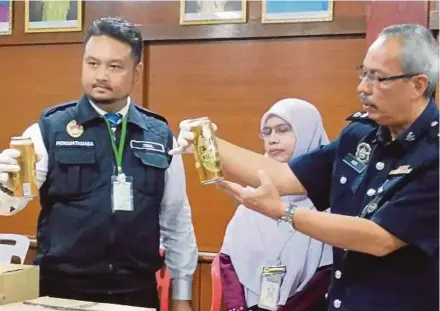  ?? PIC BY MOHD KHIDIR ZAKARIA ?? Port Dickson district police chief Superinten­dent Aidi Sham Mohamed (right) showing the alcoholic drink at a press conference in Port Dickson yesterday.