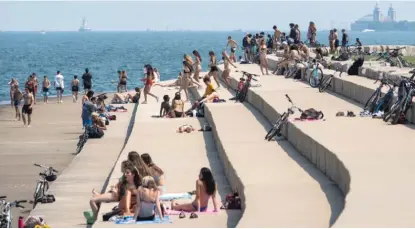  ?? ASHLEE REZIN GARCIA/SUN-TIMES FILE ?? Young people gather at Lake Michigan this month. A spike in Chicago’s COVID cases in the 18-to-29 age group has prompted renewed restrictio­ns on bars — and a new outreach campaign by City Hall.