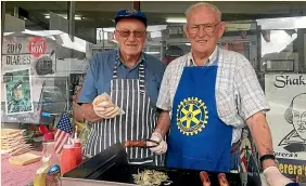  ?? CATHERINE GROENESTEI­N/STUFF ?? Stratford Rotary Club members Barrie Smith and Gordon Gibbons serving up sausages on Stratford’s main street.