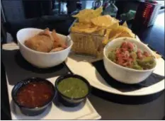  ??  ?? Two appetizers, the Beef Empanadas, left, and Guacamole, ordered at the bar at Trilogy are arranged on a tray before being taken by a staffer into a movie auditorium.