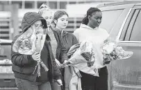  ?? ?? People bring flowers to a makeshift memorial outside Oxford High School in Michigan. Ethan Crumbley, 15, has been charged with murder and terrorism in the mass shooting.