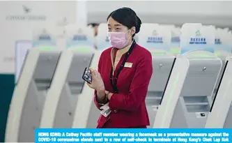  ??  ?? HONG KONG: A Cathay Pacific staff member wearing a facemask as a preventati­ve measure against the COVID-19 coronaviru­s stands next to a row of self-check in terminals at Hong Kong’s Chek Lap Kok Internatio­nal Airport on Tuesday. —AFP