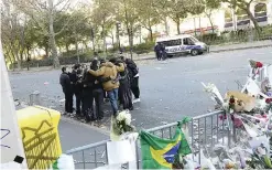  ??  ?? People huddle together at a memorial set up along a police cordon close to the Bataclan concert hall yesterday, two days after a series of deadly attacks. —AFP