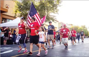  ?? Michelle Logan /For The Signal ?? Team Red, White and Blue athletic director Jaclyn Pieper leads a group of relay participan­ts into the Westfield Valencia Town Center on Thursday.