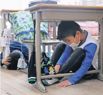  ?? FOTO: REUTERS ?? Schutz unterm Schulpult: Kinder bei einer Erdbeben-Übung gestern in Tokio.