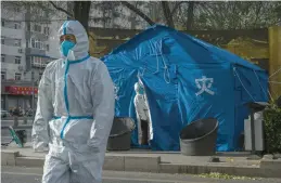  ?? KEVIN FRAYER/GETTY ?? Workers on Tuesday in Beijing wear personal protective gear to ward off COVID-19. Police in Beijing and several other Chinese cities are working to quell protests.