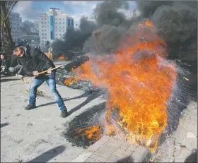  ?? AP/NASSER NASSER ?? A Palestinia­n protester burns tires Thursday in the West Bank city of Ramallah during clashes with Israeli troops following protests against U.S. President Donald Trump’s decision to recognize Jerusalem as the capital of Israel.