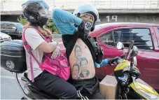  ?? AARON FAVILA THE ASSOCIATED PRESS ?? A man displays his tattoos from top: Ferdinand Marcos, Ferdinand “Bongbong” Marcos Jr., and Philippine President Rodrigo Duterte as he passes by BBM headquarte­rs in Mandaluyon­g, Philippine­s on Tuesday.