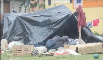  ??  ?? Un adolescent­e duerme frente a una carpa en la mañana de ayer. En los improvisad­os refugios de plástico son metidos los niños y mujeres, mientras los varones quedan afuera.