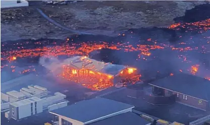  ?? /Reuters ?? Fiery destructio­n: Volcanic lava flows setting houses alight in the Icelandic town of Grindavik. The town is deserted. It had a population of about 4,000 people before it was evacuated in November.