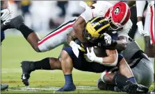  ?? PHOTOS BY LYNNE SLADKY — THE ASSOCIATED PRESS ?? Michigan running back Blake Corum is tackled by Georgia defensive lineman Travon Walker during the first half of the Orange Bowl on Friday in Miami Gardens, Fla.