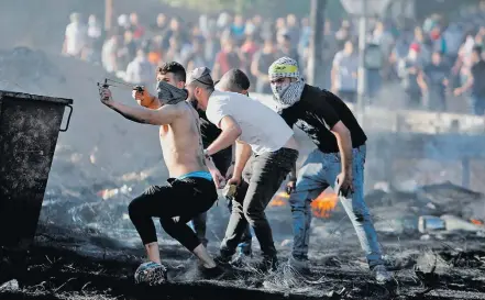  ?? RANEEN SAWAFTA / REUTERS ?? Revolta. Palestinos jogam pedras contra posto de controle israelense na Cisjordâni­a, onde houve greve e manifestaç­ões