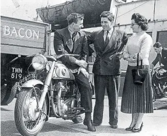  ??  ?? The late Geoff Duke (centre) chats to a Norton Dominator 88 rider at Douglas Harbour during TT fortnight as another machine is rolled down the ramp of one of the Isle of Man Steam Packet Company’s long-lost steam-turbine ferries. Mortons Motorcycle Archive photo.