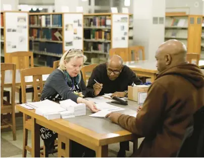  ?? ?? Tax preparers Donna Tuke, from left, and Hersi Suleiman from the Center for Economic Progress help Jerome Artis with his tax return at the Evanston Public Library in Evanston, Illinois.