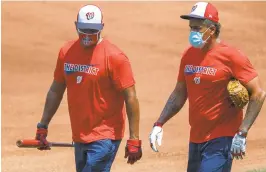  ?? CAROLYN KASTER/AP ?? Nationals manager Dave Martinez, left, and bullpen coach Henry Blanco walk together during a workout Sunday at Nationals Stadium. Monday’s practice was canceled.