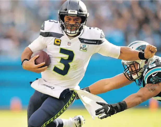  ?? — PHOTOS: GETTY IMAGES ?? Seattle Seahawks quarterbac­k Russell Wilson is pressured by Wes Horton of the Carolina Panthers Sunday in Charlotte, N.C. Wilson had a strong afternoon; he threw for a pair of touchdowns and 339 yards in rallying the Seahawks to a 30-27 victory.