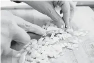  ??  ?? A member chops garlic for a dish that will be shared by everyone. Per serving costs are as low as 60 cents.