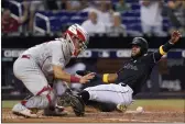  ?? WILFREDO LEE — THE ASSOCIATED PRESS ?? The Miami Marlins’ Bryan De La Cruz, right, slides into home to score as Philadelph­ia Phillies catcher Rafael Marchan waits for the throw during the sixth inning Friday in Miami. De La Cruz and Joe Panik scored on a single by Miguel Rojas.