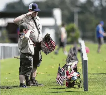  ?? Elizabeth Conley / Houston Chronicle ?? Members of Boy Scout Troop 92 salute a tombstone Sunday after garnishing it with a flag at Houston National Cemetery at a Memorial Day event coordinate­d by Flags for Fallen Vets.