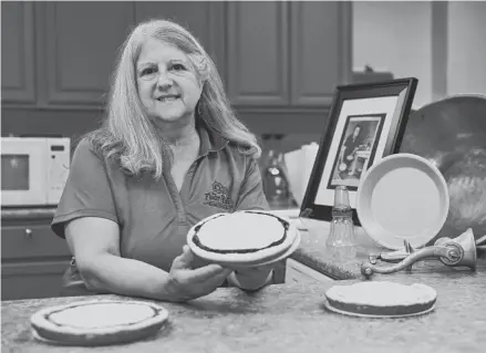  ?? SARAH KLOEPPING/USA TODAY NETWORK-WISCONSIN ?? Gina Guth, owner of The Flour Pot, holds a Belgian pie made using her mother’s recipe. She is sitting next to the original baking tools she used to help make pies as a child.