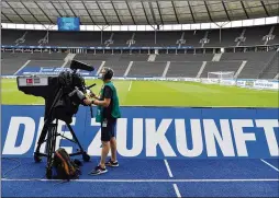  ?? POOL PHOTO VIA AP ?? A cameraman works in front of empty stands in Berlin prior to a match between Hertha BSC Berlin and Eintracht Frankfurt. Because of the coronaviru­s outbreak, all Bundesliga matches take place without spectators, but TV broadcasts include artificial crowd noise that has drawn mixed reaction from fans.