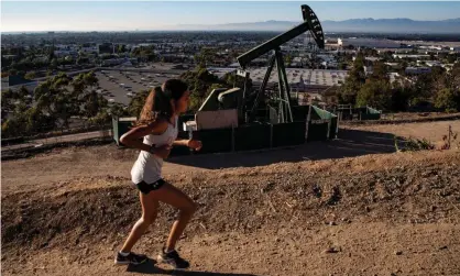  ?? Photograph: Étienne Laurent/EPA ?? A woman runs next to a pumpjack in Los Angeles.