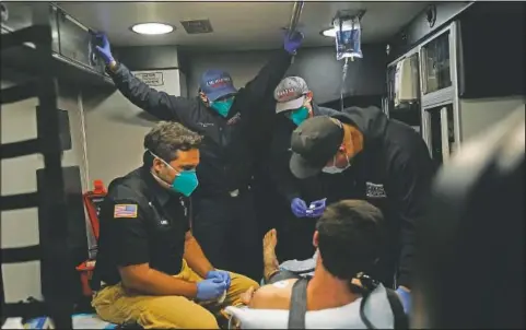  ??  ?? Emergency medical workers Trenton Amaro (from left), Hammond, Hoang and Charles Navarro are crammed in an ambulance as they treat a patient in Placentia, Calif.