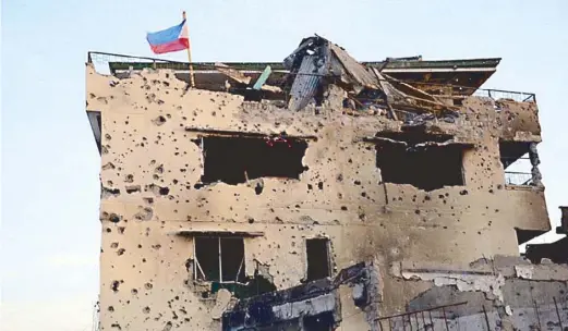  ??  ?? The Philippine flag waves from atop after government forces retook a building where MNLF forces had holed up.