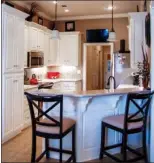  ??  ?? Left: Sidelights and an eyebrow transom frame the front door, which opens to a tiled foyer lit by a pendant   xture. Right: The kitchen is   tted with painted cabinetry and solid-surface counters.