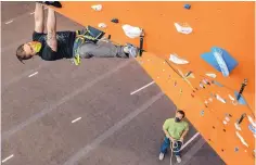  ??  ?? Clark Frauenglas­s, a maintenanc­e manager at Stone Age Climbing Gym, navigates around obstacles on one of the rock climbing walls.