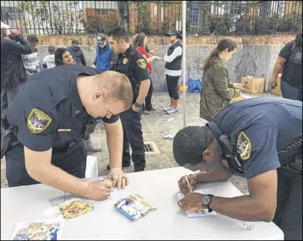  ?? CONTRIBUTE­D BY THE PACKAGED GOOD. ?? Dunwoody police officers stopped by The Packaged Good’s MLK Day of Service to write cards to families served by the Community Assistance Center and other organizati­ons.