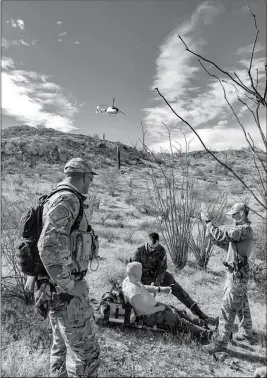  ?? PHOTO COURTESY OF CBP ?? A WELLTON AGENT, A BORSTAR AGENT AND A BORSTAR EMT aid 77-year-old Gregory Manary, who had been lost since Saturday, while a DPS helicopter arrives.