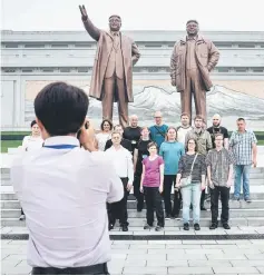  ??  ?? Tourists pose for a group photo before statues of late North Korean leaders Kim Il-Sung (left) and Kim Jong-Il (right), on Mansu hill in Pyongyang. — AFP photo