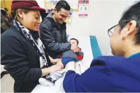  ?? ASSOCIATED PRESS FILE PHOTO ?? Matilde Gonzalez, left, and Cesar Calles hold their 10-month-old son, Cesar Julian Calles, as Ana Martinez gives him a flu shot in Seattle earlier this month.