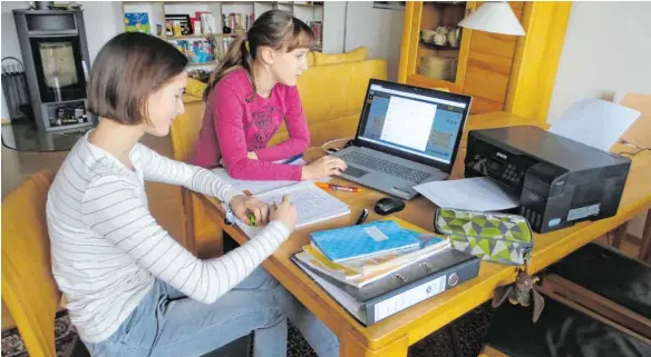  ?? FOTO: MÖCKLIN ?? Mit Laptop und Drucker im Wohnzimmer: So sieht für Amelie (14) und Sophie (12) der Schulallta­g in Corona-Zeiten aus.