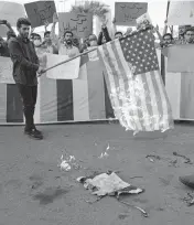  ?? VAHID SALEMI AP ?? A group of hardline students burn the U.S. and Israeli flags during their gathering to condemn President Biden’s tour to the Middle East, on Saturday, in Tehran, Iran.