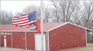  ?? Westside Eagle Observer/MIKE ECKELS ?? Heavy winds cause the flags at Decatur City Hall to whip around as blowing snow begins accumulati­ng near the Decatur Fire Department. The backside of Winter Storm Malcolm produced 30-45 mile per hour winds, causing snowy conditions in Northwest Arkansas.