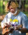  ??  ?? Camper Syd Anderson, 14, of Edina, who uses they/them pronouns, plays the ukulele before dinner at Camp True Colors in July.