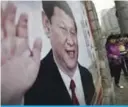  ?? — AP ?? BEIJING: Women walk by a poster featuring Chinese President Xi Jinping in Beijing.