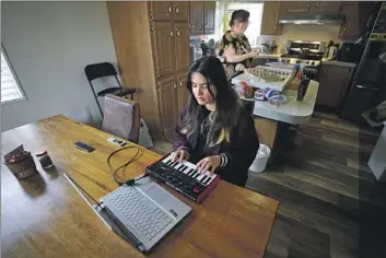  ?? Rich Pedroncell­i KFF Health News ?? SUMMER ORIYAVONG uses a keyboard while her mother, Sheri, cooks at their home in Rio Linda, north of Sacramento. Oriyavong loves music and says it helps her deal with her schizophre­nia symptoms.