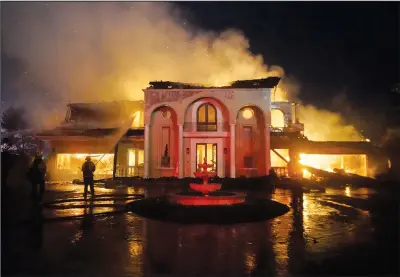  ?? ?? Firefighte­rs work to put out a structure fire Wednesday during a wildfire in Laguna Niguel.