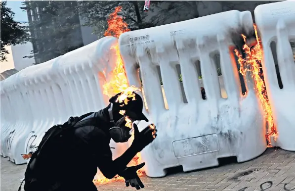  ??  ?? An anti-government protester catches fire after throwing a petrol bomb at a barricade during a demonstrat­ion near the Central Government Complex in Hong Kong