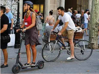  ?? ?? Gente paseando con patinetes por la ciudad.