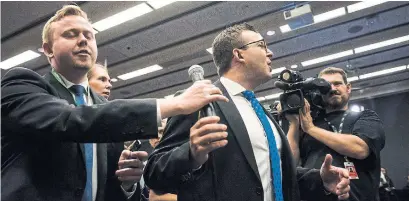  ?? CHRISTOPHE­R KATSAROV/THE CANADIAN PRESS ?? A press officer pulls a microphone away from a reporter trying to pose a question to Premier Doug Ford.