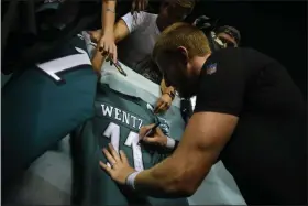  ?? MIKEY REEVES — FOR MEDIANEWS GROUP ?? Eagles quarterbac­k Carson Wentz puts his autograph on a jersey for fans gathered at the Eagles’ practice at Lincoln Financial Field Sunday night.