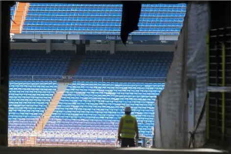  ?? PAUL WHITE — THE ASSOCIATED PRESS ?? Workers walk into Real Madrid’s Santiago Bernabeu stadium in Madrid, Spain on Monday. Spanish league clubs are now allowed to train with groups of up to 14players as the league stays on track to restart the season in less than three weeks.