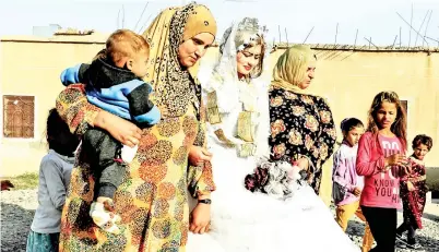  ??  ?? Syrian women escort bride Heba (centre) as they participat­e in celebratio­ns during the first wedding after the ouster of the Islamic State (IS) group from the eastern city of Raqa, in the western suburb of Jazra. — AFP photo