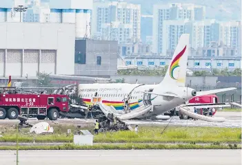  ?? LIU CHAN/XINHUA ?? The wreckage of a Chinese passenger jet that veered off a runway during an aborted takeoff and caught fire Thursday is examined by emergency workers. Chinese civil aviation officials said more than 30 people were injured when the Tibet Airlines
jet, with 122 people on board, left the runway at Chongqing Jiangbei Internatio­nal Airport in Chongqing.